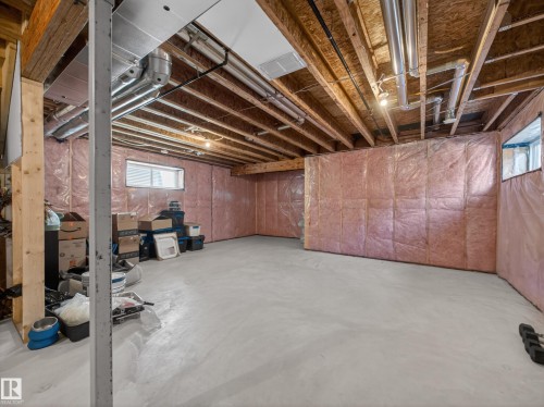 Expansive unfinished basement featuring exposed wooden beams, concrete flooring, and insulated walls - 3210 Chernowski Way, Edmonton, AB - Indoor Photo Showing Basement