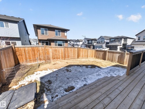 The property features a private backyard enclosed by a wood fence, with a deck visible in the foreground - 3210 Chernowski Way, Edmonton, AB - Outdoor With Deck Patio Veranda