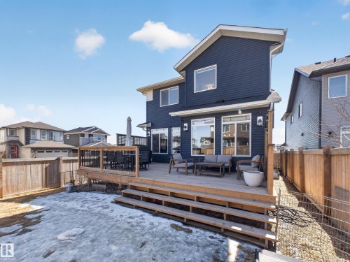 The property features a dark blue exterior with white trim and a multi-level wooden deck - 3210 Chernowski Way, Edmonton, AB - Outdoor With Deck Patio Veranda
