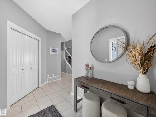 Entryway featuring light-colored tile flooring, a white bi-fold closet, and a partial view of a staircase with white railings - 3210 Chernowski Way, Edmonton, AB - Indoor Photo Showing Other Room