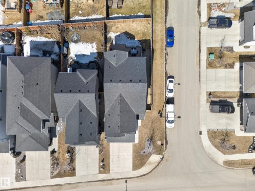 Aerial view of the property and its surrounding neighborhood, showcasing the property's grey shingled roof, attached driveway, and a front yard with minimal landscaping - 3210 Chernowski Way, Edmonton, AB - 