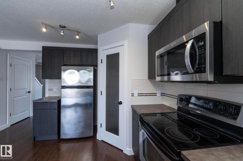 The kitchen features dark wood cabinetry, stainless steel appliances, and sleek countertops - 197 Birchwood Close, Devon, AB - Indoor Photo Showing Kitchen