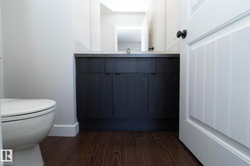 This bathroom features a contemporary dark wood vanity with a light-colored countertop, complemented by dark wood-style flooring - 197 Birchwood Close, Devon, AB - Indoor Photo Showing Bathroom