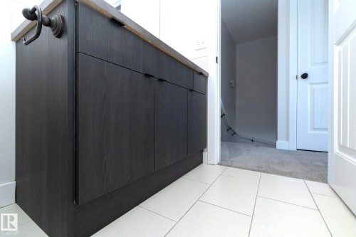 This space features a dark wood vanity with a light-colored countertop and light-colored tiled flooring - 197 Birchwood Close, Devon, AB -  Photo Showing Other Room
