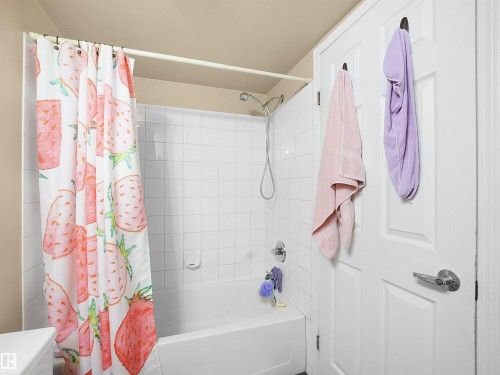 The bathroom features a bathtub with white tiled walls and a shower head - 10 10331 106 Street, Edmonton, AB - Indoor Photo Showing Bathroom