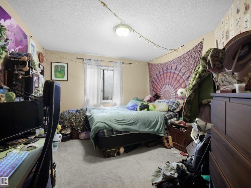 This room features a window with white curtains and carpeted flooring - 10 10331 106 Street, Edmonton, AB - Indoor Photo Showing Bedroom