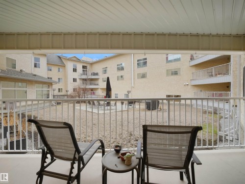 This property features a covered balcony with a white railing, offering views of the exterior grounds and surrounding buildings - 10 10331 106 Street, Edmonton, AB - Outdoor