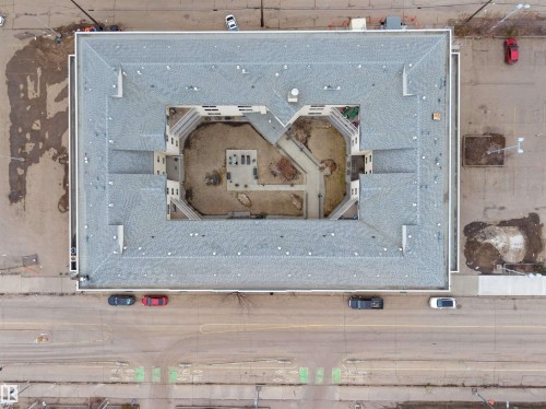 The property features an inner courtyard with paved pathways and seating areas, surrounded by residential units - 10 10331 106 Street, Edmonton, AB - 