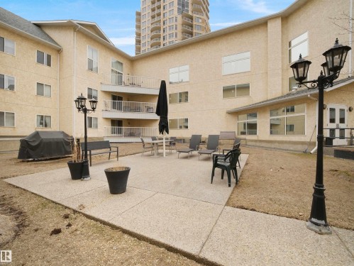 The property features an outdoor patio area with concrete paving, seating, and outdoor lighting fixtures - 10 10331 106 Street, Edmonton, AB - Outdoor With Exterior