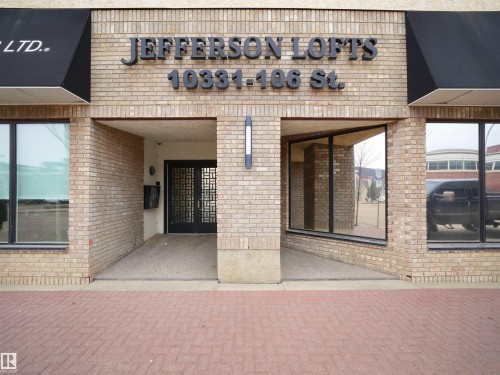 The property features an exterior of light-colored brickwork and expansive storefront windows - 10 10331 106 Street, Edmonton, AB - Outdoor