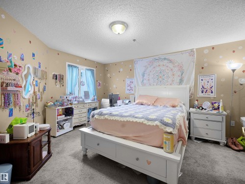 This room features neutral-toned walls, a window with curtains, and a ceiling light fixture - 10 10331 106 Street, Edmonton, AB - Indoor Photo Showing Bedroom