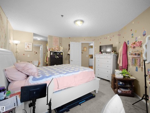 The room features a neutral color palette with light beige walls and a light-colored carpeted floor - 10 10331 106 Street, Edmonton, AB - Indoor Photo Showing Bedroom