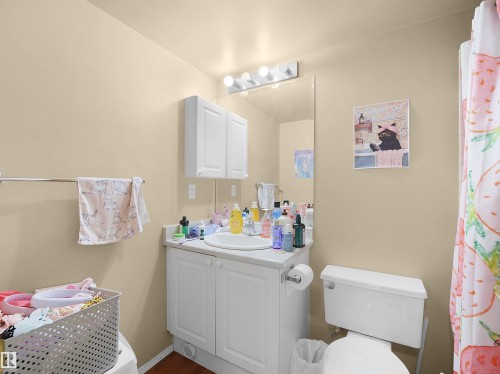 The bathroom features a white vanity with a single sink, a wall-mounted medicine cabinet, and a white toilet - 10 10331 106 Street, Edmonton, AB - Indoor Photo Showing Bathroom
