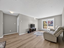 The living room features light wood-style flooring, light grey walls, and a sliding glass door leading to the outdoors - 