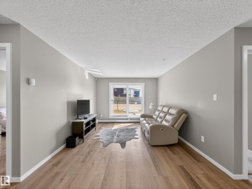 Living area featuring light grey walls, light wood-style flooring, and a sliding glass door leading to the exterior - 124 148 Ebbers Boulevard, Edmonton, AB - Indoor Photo Showing Living Room