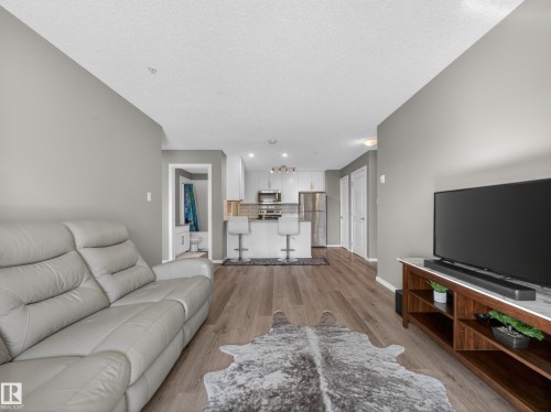 Spacious open concept living area featuring light-toned walls and hardwood style flooring - 124 148 Ebbers Boulevard, Edmonton, AB - Indoor Photo Showing Living Room