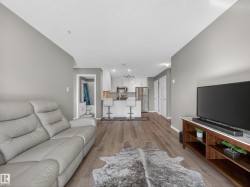 Spacious open concept living area featuring light-toned walls and hardwood style flooring - 