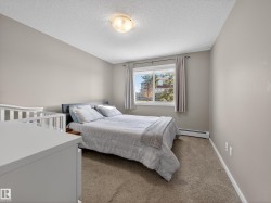 Bedroom featuring a window with a view of external buildings and trees, a ceiling light fixture, and carpeted flooring - 