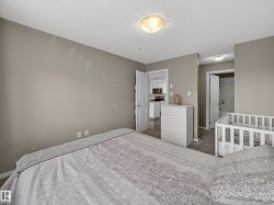 The bedroom features neutral-toned walls, carpet flooring, and a ceiling light fixture - 