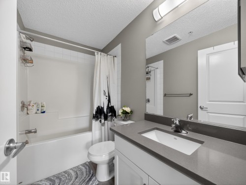 Bathroom featuring a white bathtub, a toilet, and a vanity with a rectangular sink and a grey countertop - 124 148 Ebbers Boulevard, Edmonton, AB - Indoor Photo Showing Bathroom
