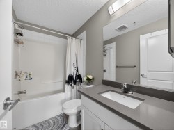 Bathroom featuring a white bathtub, a toilet, and a vanity with a rectangular sink and a grey countertop - 