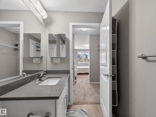 Bathroom featuring a vanity with a white rectangular sink and chrome faucet, under-sink storage, and a mirror extending across the length of the vanity - 124 148 Ebbers Boulevard, Edmonton, AB - Indoor Photo Showing Bathroom