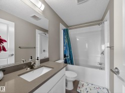 Bathroom featuring a vanity with a rectangular sink, a bathtub with a shower, and a toilet - 