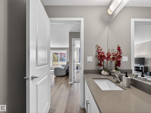 Bathroom vanity featuring a single sink and a long countertop, with a mirror extending across the wall - 124 148 Ebbers Boulevard, Edmonton, AB - Indoor Photo Showing Bathroom