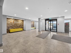 The building entrance features large format tile flooring, recessed lighting, and a modern accent wall with a built-in bench - 