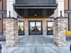 The property features an entrance with stone pillar accents, large glass doors, and exterior lighting fixtures - 