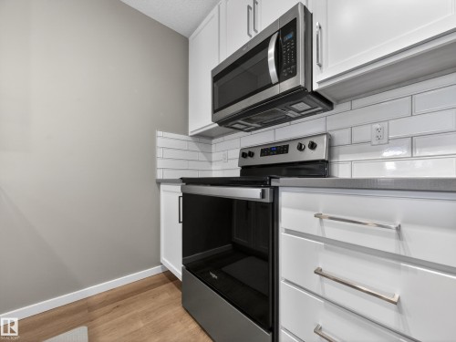 Kitchen featuring white cabinetry, stainless steel appliances, a white subway tile backsplash, and light wood flooring - 124 148 Ebbers Boulevard, Edmonton, AB - Indoor Photo Showing Kitchen