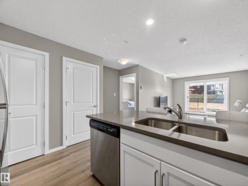Kitchen featuring a dual basin stainless steel sink, a stainless steel dishwasher, and light-colored countertops - 124 148 Ebbers Boulevard, Edmonton, AB - Indoor Photo Showing Kitchen With Double Sink