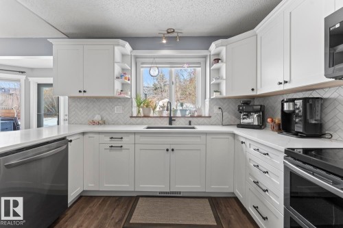 The kitchen features white cabinetry, quartz countertops, and a herringbone-patterned tile backsplash - 1929 Forest Drive, Cold Lake, AB - Indoor Photo Showing Kitchen