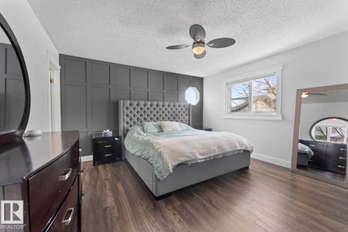 The bedroom features vinyl plank flooring, a decorative accent wall, a window providing natural light, and a ceiling fan with a walk-in closet. - 1929 Forest Drive, Cold Lake, AB - Indoor Photo Showing Bedroom