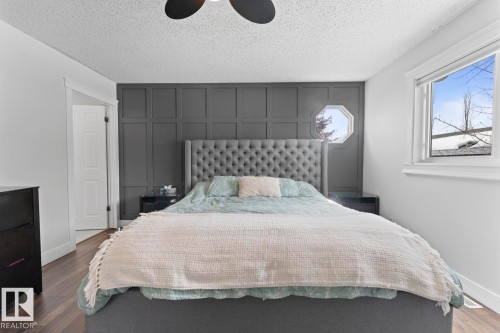 This room features vinyl plank flooring, white walls, and a distinctive dark panelled accent wall with an octagonal window - 1929 Forest Drive, Cold Lake, AB - Indoor Photo Showing Bedroom