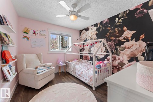 The room features a window with natural light, dark vinyl plank floors, and a ceiling fan - 1929 Forest Drive, Cold Lake, AB - Indoor Photo Showing Bedroom
