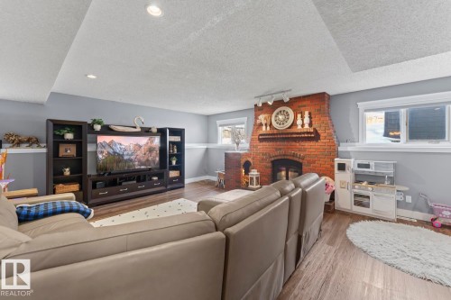 This living area features a brick fireplace, recessed lighting, and windows providing natural light - 1929 Forest Drive, Cold Lake, AB - Indoor Photo Showing Living Room With Fireplace