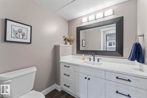 The bathroom features a white vanity with a quartz  countertop and black hardware, a black framed mirror with overhead lighting - 1929 Forest Drive, Cold Lake, AB - Indoor Photo Showing Bathroom