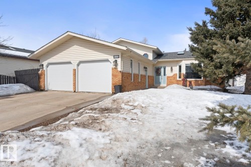 The property features a two-car garage with white doors, a concrete driveway, and an exterior combining light-colored siding and brick accents - 1929 Forest Drive, Cold Lake, AB - Outdoor