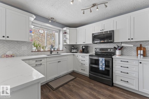 The kitchen features white cabinetry, white quartz countertops, and a white herringbone tile backsplash - 1929 Forest Drive, Cold Lake, AB - Indoor Photo Showing Kitchen