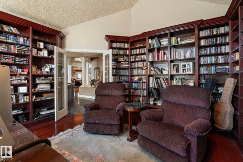 This room features extensive built-in wooden bookshelves, hardwood flooring, and a vaulted ceiling - 9610 167 Street Sw, Edmonton, AB - Indoor