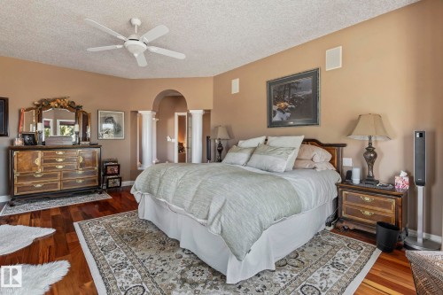 Bedroom featuring hardwood floors, a ceiling fan, and an arched entry with columns - 9610 167 Street Sw, Edmonton, AB - Indoor Photo Showing Bedroom
