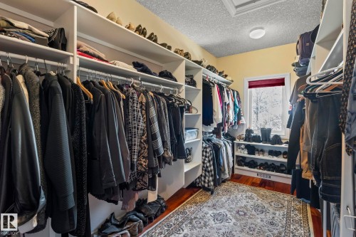 Spacious closet featuring custom built-ins, ample shelving, rich hardwood floors, and a window providing natural light - 9610 167 Street Sw, Edmonton, AB - Indoor With Storage
