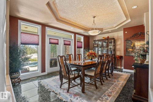 This formal dining area features an ornate chandelier, a tray ceiling, and tile flooring - 9610 167 Street Sw, Edmonton, AB - Indoor Photo Showing Dining Room