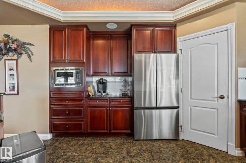 Kitchen area featuring rich wood cabinetry, integrated stainless steel microwave, and a stainless steel French door refrigerator - 9610 167 Street Sw, Edmonton, AB - Indoor Photo Showing Kitchen