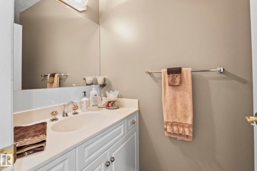 Bathroom vanity featuring a built-in sink with a polished faucet, white cabinetry, and a large wall mirror - 9610 167 Street Sw, Edmonton, AB - Indoor Photo Showing Bathroom