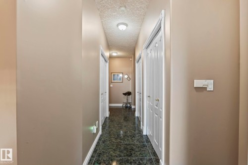 The property features a hallway with dark tiled flooring, light beige walls, and white trim - 9610 167 Street Sw, Edmonton, AB - Indoor Photo Showing Other Room