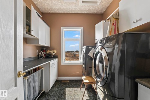 The laundry area features front-loading appliances, ample cabinetry for storage, and a window providing natural light - 9610 167 Street Sw, Edmonton, AB - Indoor Photo Showing Laundry Room