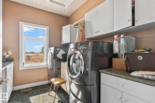 This well-equipped utility room features a window providing natural light, white cabinetry for storage, and a durable tiled floor - 9610 167 Street Sw, Edmonton, AB - Indoor Photo Showing Laundry Room