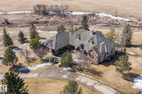The property features a large residence with a multi-gabled roof and brick detailing, set amidst a landscaped yard with mature evergreen trees - 9610 167 Street Sw, Edmonton, AB - Outdoor With View